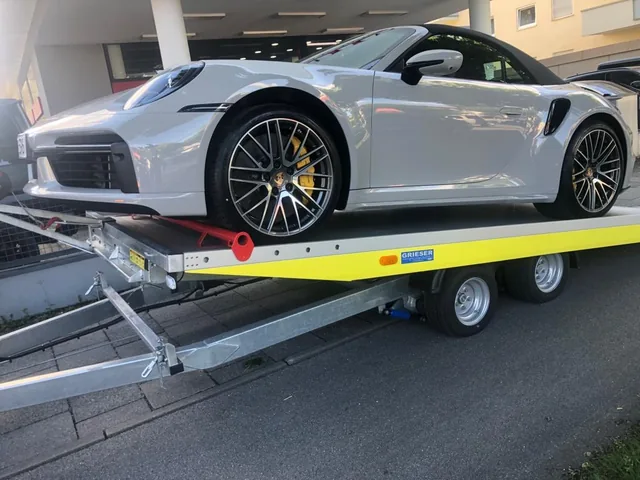 Silberner Porsche 911 auf einem offenen Fahrzeuganhänger