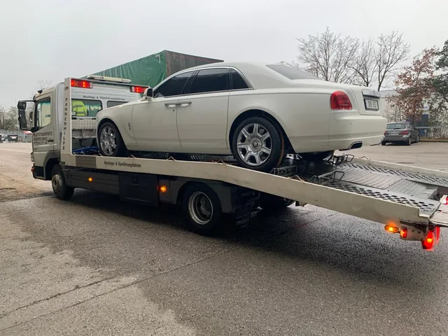 Weißer Rolls-Royce auf einem Mercedes Atego Transportfahrzeug