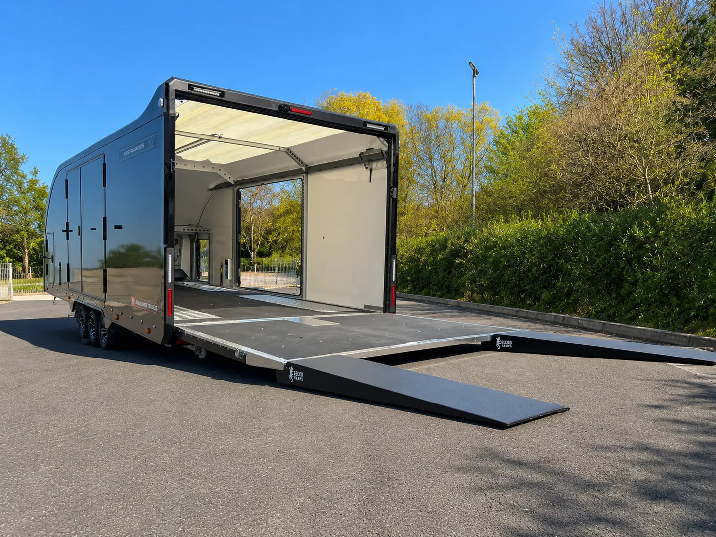 Geöffneter geschlossener Premium-Fahrzeugtrailer mit ausgefahrener Laderampe