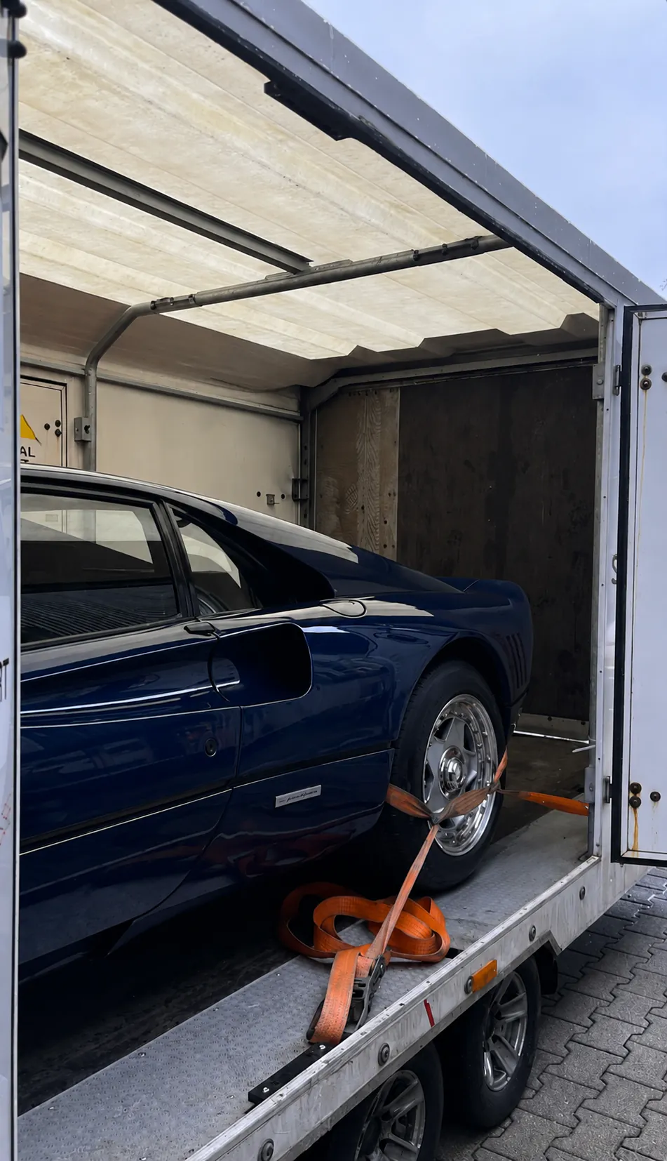 Blauer Ferrari gesichert in einem geschlossenen Fahrzeugtransporter; kein Kennzeichen sichtbar