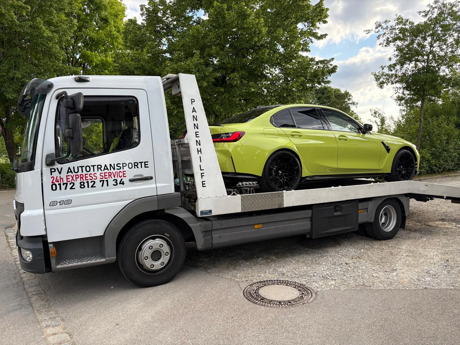 Grüne BMW M3 Limousine auf einem PV Transportfahrzeug
