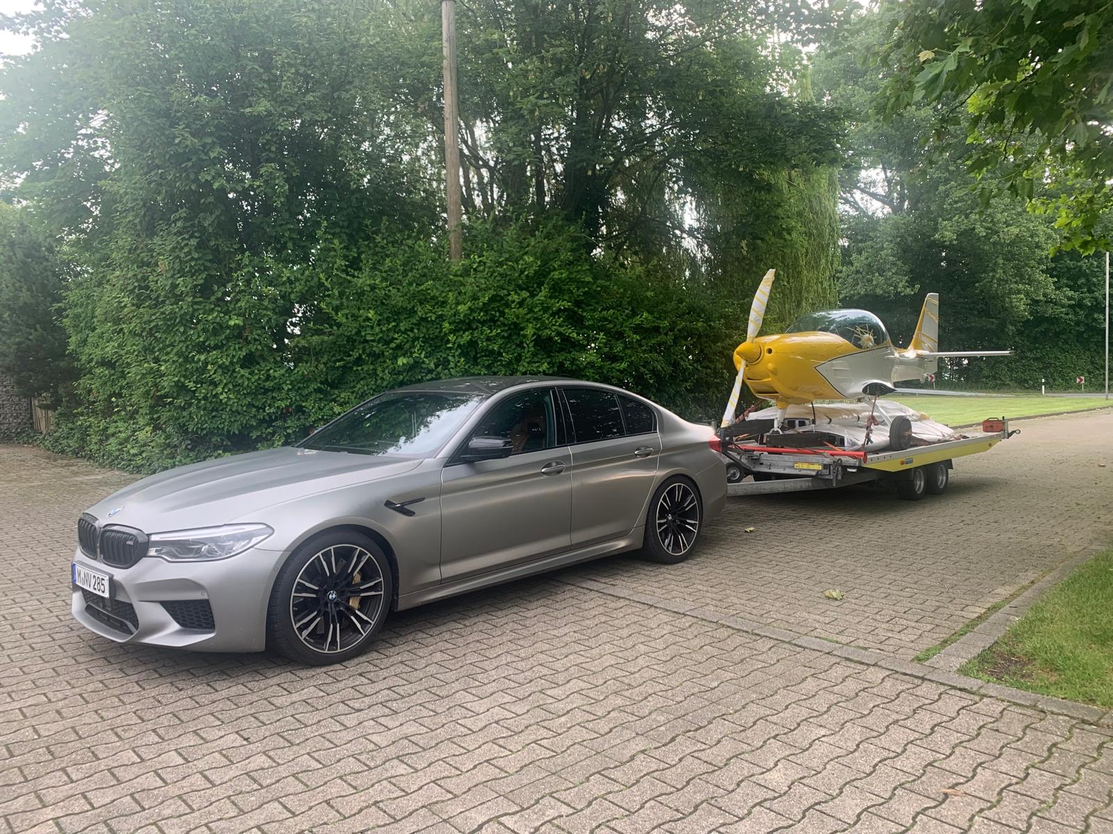 BMW M5 Limousine vor einem Flugzeug im Hintergrund