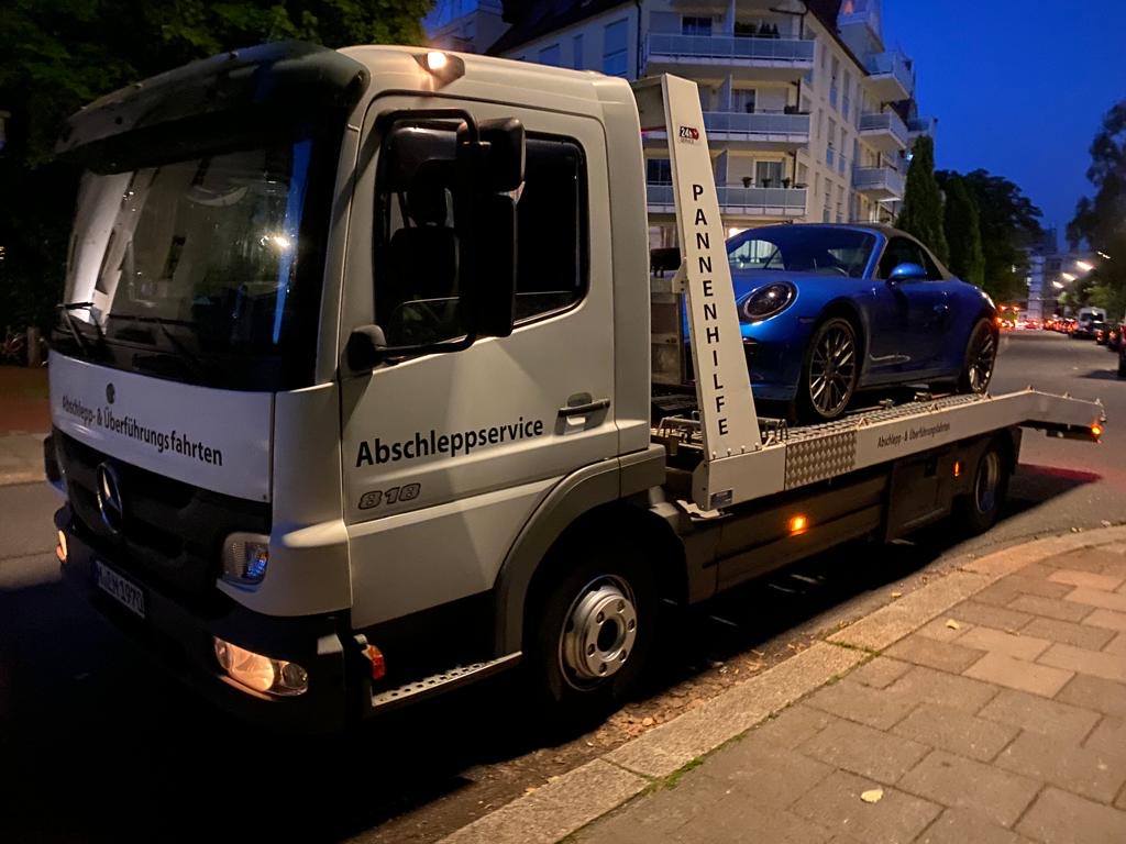 Blauer Porsche 911 auf einem PV Transportfahrzeug bei Nacht