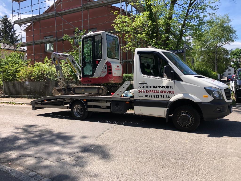 Kompaktbagger auf einem PV Transportfahrzeug