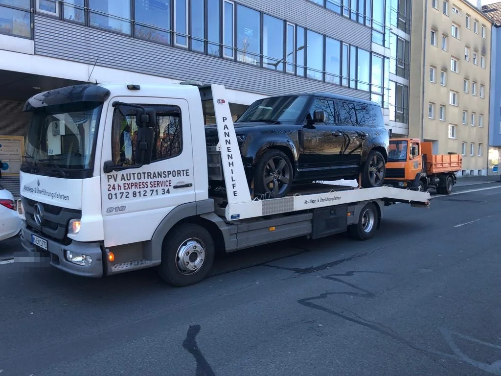 Land Rover Defender auf einem PV Transportfahrzeug